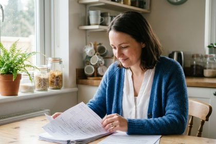 Femme en cardigan bleu et blouse blanche étudiant des documents santé